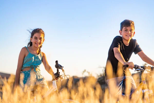 Two kids on a bike in front of a wheat field