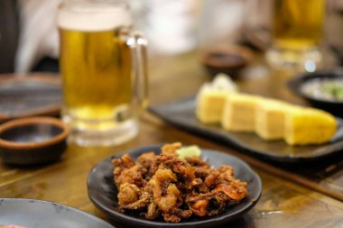 Japon restoranında kızarmış kalamar servis edilir. Arka planda bira ve diplated