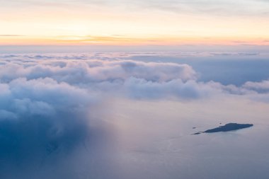 Renkli gökyüzü ve bulutlar uçağın penceresinden görünüyor