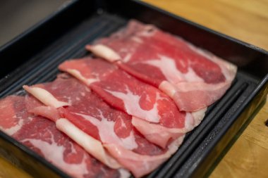 Dilimlenmiş çiğ eti yakın, sıcak tencere tarafından pişirilmeye hazır.