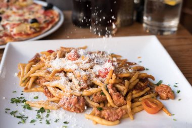 Domates soslu makarna, serpiştirilmiş peynir. Restoranda tabakta..