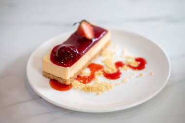 Tabakta soslu ve parçalanmış çilekli cheesecake.