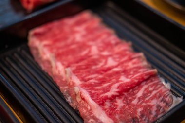 Dilimlenmiş çiğ eti yakın, sıcak tencere tarafından pişirilmeye hazır.