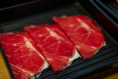 Angus Chuck Roll 'a peynirli yakın çekim. Çiğ et, sıcak tencere tarafından pişirilmeye hazır.