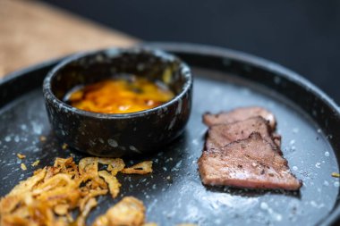 Kızarmış sarımsak ve yumurta sarısı ile servis edilen sığır dili eti..