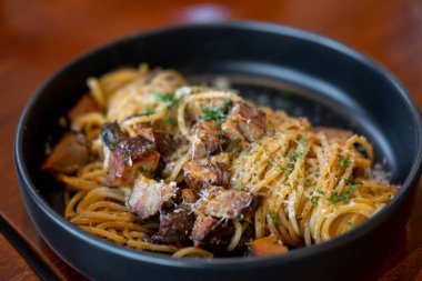 Spagetti füme domuz eti ile parmesk peyniri tabakta servis edilir.