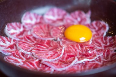 Dilimlenmiş biftek, yumurta sarısı bir kasede servis edilir. Sıcak tencere için hazır, Shabu Asya usulü.