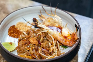 Tabağında nehir karidesi olan Pad Thai. Kızarmış pirinç eriştesi Tayland yemeği.