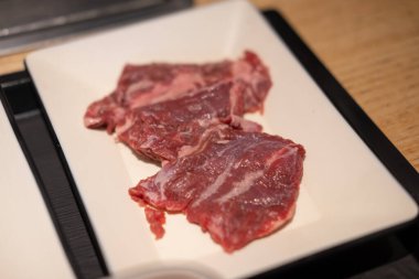 Tabakta, paslanmaz ızgaranın önünde Kore usulü barbekü. Yumuşak odaklı az pişmiş et.