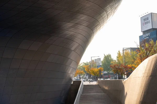 stock image Seoul, South Korea - 30 October 2023: Walkway and Perforated facade cladding of Dongdaemun Design Plaza or DDP with beautiful autumn foliage. It is designed by Zaha Hadid and Samoo