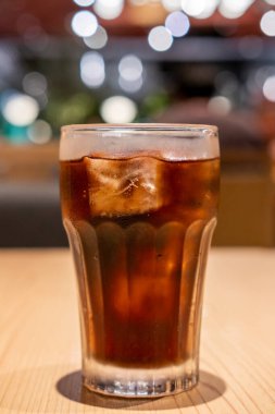 Masada bir bardak kola ve bokeh arkaplan.