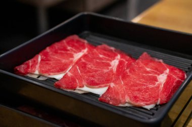 Angus Chuck Roll 'a peynirli yakın çekim. Çiğ et, sıcak tencere tarafından pişirilmeye hazır.