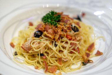 Beyaz tabakta servis edilen baharatlı pastırmalı spagetti. Yumuşak Odaklanma.