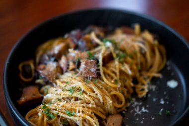 Spagetti füme domuz eti ile parmesk peyniri tabakta servis edilir.