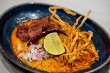 Khao Soi, Tayland usulü körili şehriye çorbası ve kasede servis edilen et.