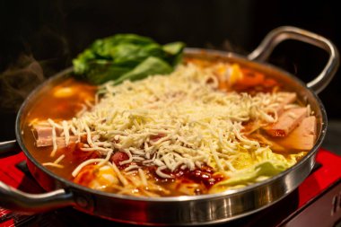 Korean hot pot, Ramyeon and Tteokbokki in Kimchi soup with vegetable, meat and cheese on top clipart