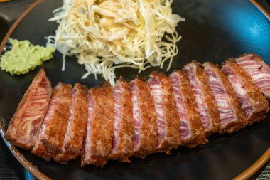 Lahanayla servis edilen Gyukatsu ya da sığır pirzolası. Kızarmış sığır pirzolasından oluşan geleneksel bir Japon yemeği. Taş ızgaranın üstünde.