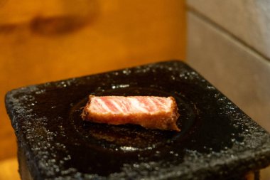 A piece of Gyukatsu or beef cutlet on the stone grill. It is traditional Japanese food that consists of a deep-fried beef cutlet. clipart
