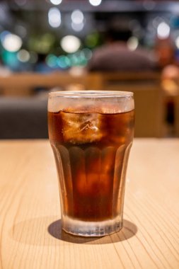 Masada bir bardak kola ve bokeh arkaplan.