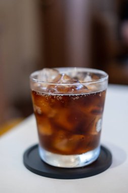 Masanın üzerinde bulanık arka planı olan bir bardak kola.