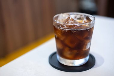 Masanın üzerinde bulanık arka planı olan bir bardak kola.