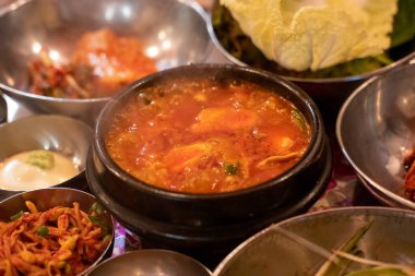 Kimchi Çorbası kasede servis edilir ve Kore mezeleri masada servis edilir.