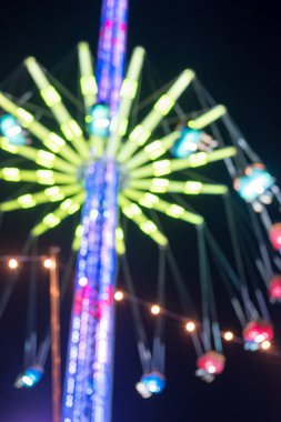 Bokeh, blurred image of Merry-go-round, chain swing carousel ride in amusement park at night clipart