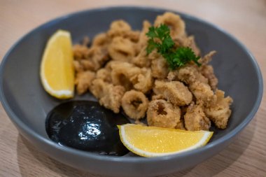 Tabakta limonlu kızarmış mürekkep balığı ya da kalamar resmi..