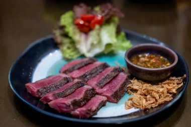 Orta pişmiş Picanha bifteği tabakta sebzeyle servis edilir.