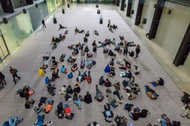 Londra, İngiltere - 21 Ekim 2016: Tate grubunun ulusal modern sanat galerisi Tate Modern Sanat Galerisi 'ndeki Türbin Salonunda yürüyen ve yatan insanlar. 21 Ekim 2016 'da Londra, Birleşik Kin