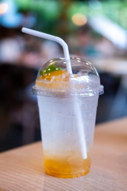 Masanın üzerinde bir bardak şeftalili soda, kafenin arka planında...