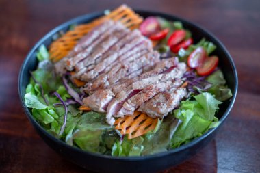 Tabakta orta pişmiş etle servis edilmiş salata.