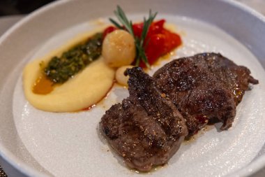 Kremalı patates püresi, fırında domates ve otlarla süslenmiş sulu ızgara biftek..