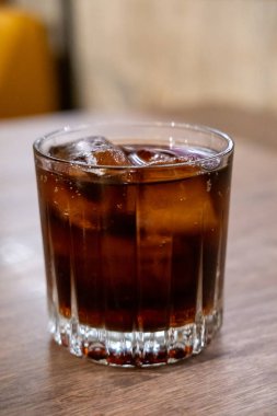 Masanın üzerinde bulanık arka planı olan bir bardak kola.