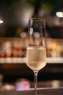 Bir bardak Prosecco ya da masada arka planda bulanık şişe görüntüsü olan köpüklü şarap.