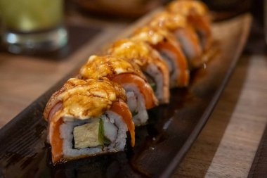 Yanmış somon suşisi rulosu ve tabakta peynir.