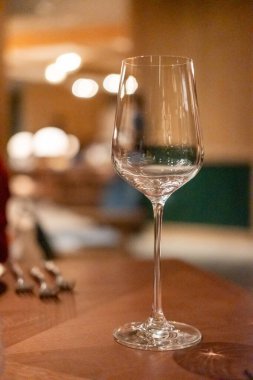 Masanın üzerinde boş şarap kadehi ve restoranın arka planı bulanık.