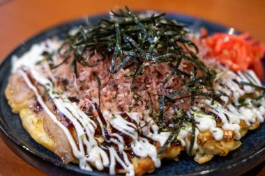 Okonomiyaki, içinde çeşitli malzemeler bulunan kurutulmuş yosun ve kurutulmuş bonito taneleriyle servis edilen Japon pizzası ya da krepi.