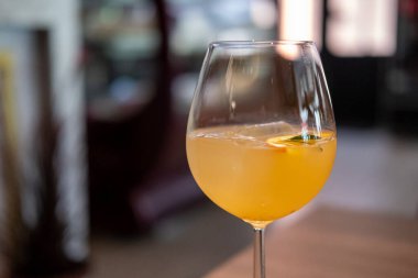 Bir bardak narenciye sangria, canlı turuncu renkte, buzlu ve bir dilim meyve garnitürlü.