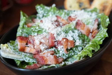 Bir kasede servis edilen dilimlenmiş pastırmalı salata, masanın üstünde.