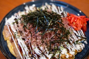 Okonomiyaki, içinde çeşitli malzemeler bulunan kurutulmuş yosun ve kurutulmuş bonito taneleriyle servis edilen Japon pizzası ya da krepi.