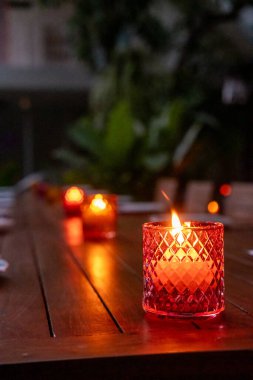 Açık hava restoranının masasında renkli camlar içinde mum.