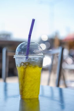 Plastik bardaktaki buzlu kasımpatı çayı, masanın üstünde.