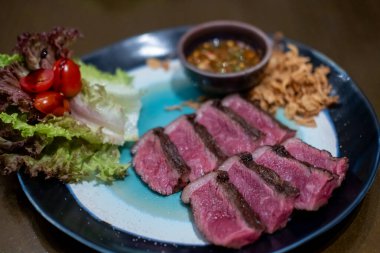 Orta pişmiş Picanha bifteği tabakta sebzeyle servis edilir.
