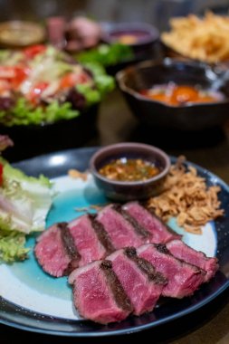 Orta pişmiş Picanha bifteği tabakta sebzeyle servis edilir.