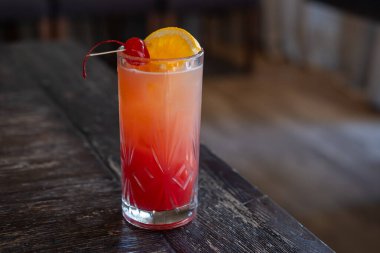 Kokteylin yakın görüntüsü, bir dilim portakal ve kiraz, masada, arka planda bokeh