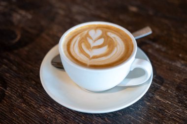 Bir fincan kahve, latte sanatıyla, masanın üstünde.