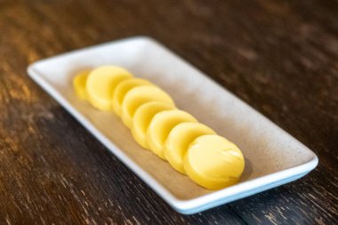 Tabakta dilimlenmiş tereyağı, ekmekle servis etmeye hazır.