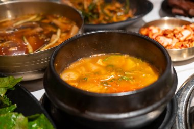 Kimchi Çorbası kasede servis edilir ve Kore mezeleri masada servis edilir.