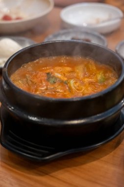 Kimchi Çorbası kasede servis edilir ve Kore mezeleri masada servis edilir.